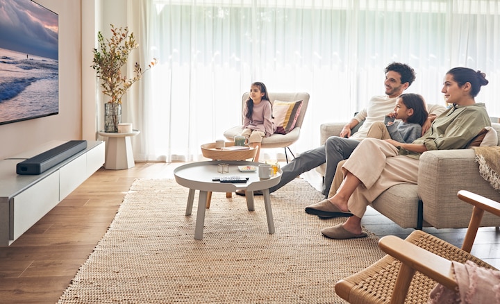 A family watching a TV with a soundbar underneath