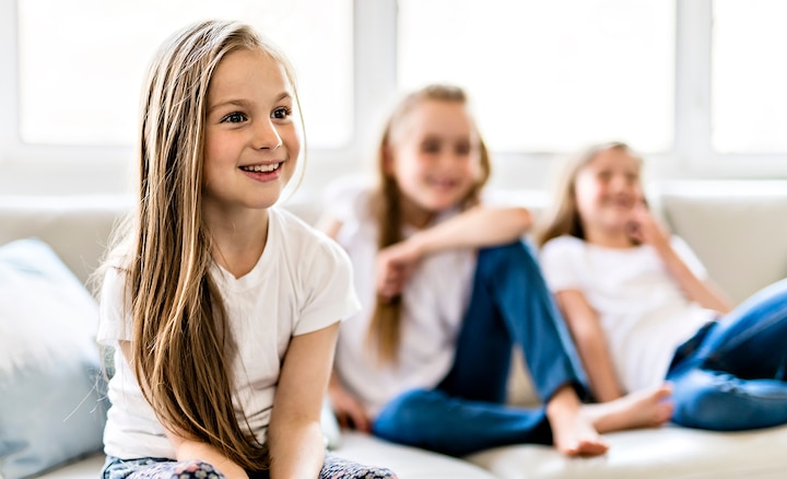 Image of three children sitting on a sofa watching TV.