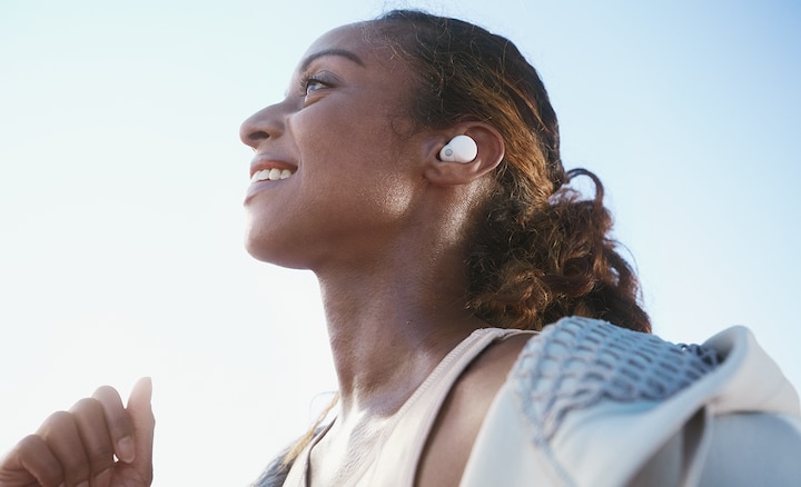 Close-up of head and shoulders of a woman wearing white LinkBuds S while running