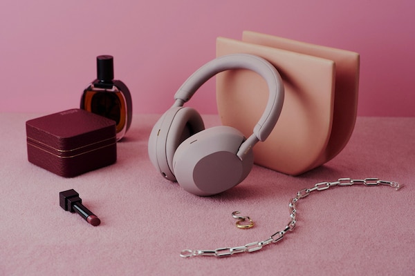 The WH-1000XM5 wireless headphones in Smoky Pink sat on a pink carpet next to beauty accessories.